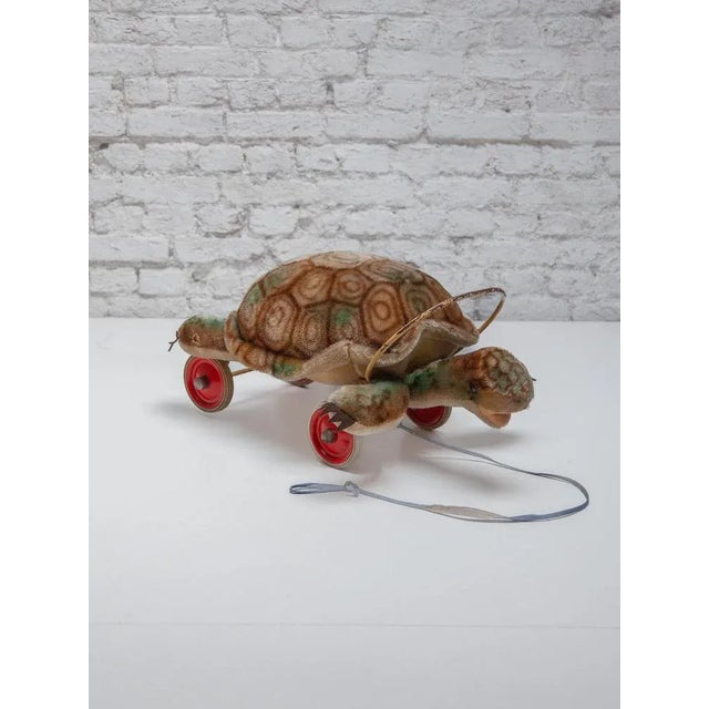A original Steiff Turtle "sit on" and "pull toy," circa 1950s. Has original pull chord and original rubber wheels with red...