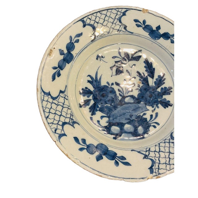 Beautiful blue and white Delft plate circa 1765. The central scene depicts a classic “rocks and flowers” garden motif —...