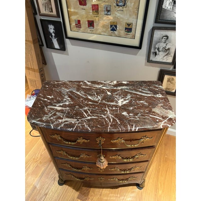 This is a Louis XIV/Regency style mahogany chest of drawers with a marble top. The inlaid wood chest has 4 drawers and a a...