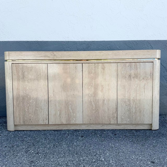A striking vintage postmodern credenza featuring a warm faux travertine laminate finish with softly rounded corners and...