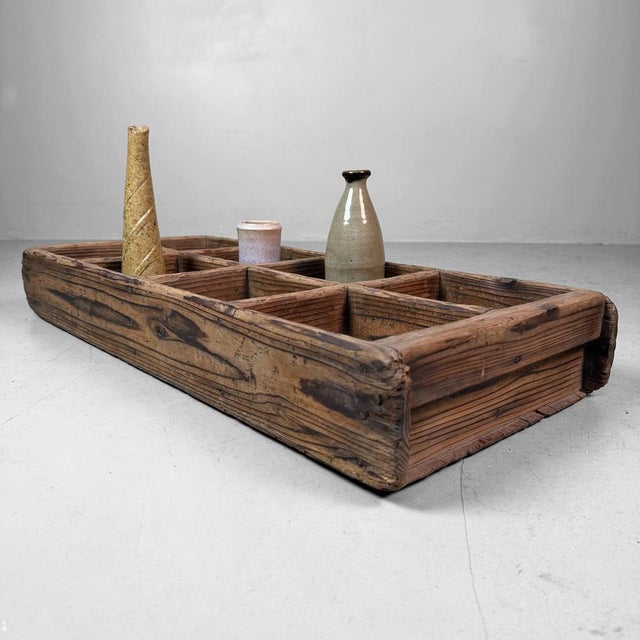 This antique Japanese wooden crate with eight compartments is a beautifully honest utilitarian piece that easily finds a...