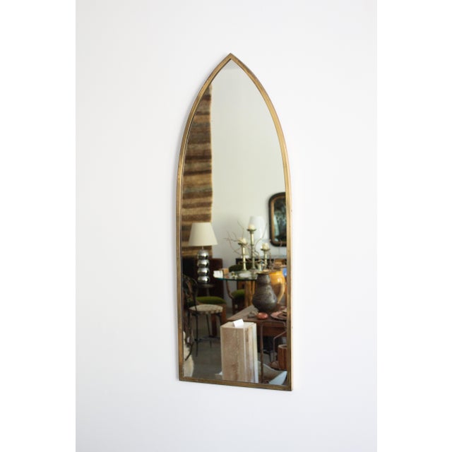 An Italian brass framed mirror circa 1950s. Cathedral arch silhouette. Tarnished patina to brass frame. In the manner of...