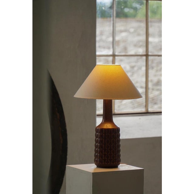 A danish ceramic table lamp produced by desire stentøj during the 1960s, featuring a richly textured cylindrical base with...