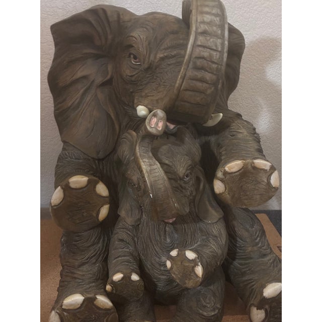 This substantial vintage molded resin sculpture depicts a mother elephant and her calf in an affectionate pose, with both...