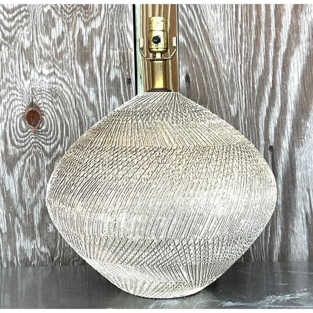 This vintage Mid-Century Modern table lamp pairs a sculptural ceramic body with warm brass hardware for a look that feels...