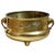 A solid brass pot with elephant head shaped handles. A motif of a mythical creature is embossed.
