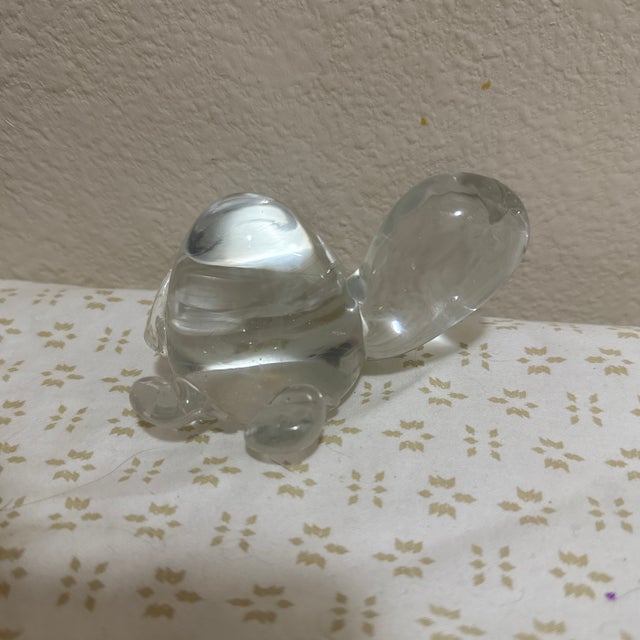 A charming glass paperweight in the form of a turtle, thoughtfully crafted with smooth contours and a balanced weight...