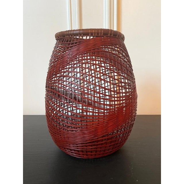 A Japanese Ikebana bamboo basket woven by artist Abe Motoshi (Japanese, b. 1942). Constructed with lacquered reddish...