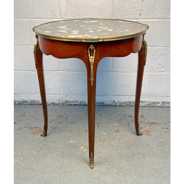 Spoil your living room with this unique French side table, crafted in the Louis XV style. The brass trim and ornamentation...