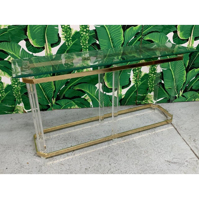 Charles Hollis Jones style console table features lucite and brass frame and glass shelf. Perfect addition to any style...