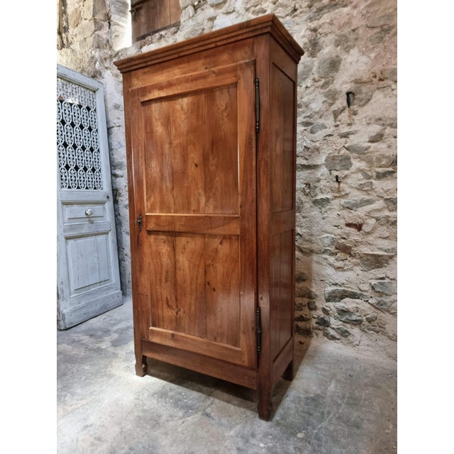 French bonnetière crafted from cherrywood, dating from the early 19th century. This tall, single-door cabinet features a...