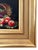 Charming petite still life depicting a tipped woven basket filled with apples and fruit, rendered in rich red, green, and...