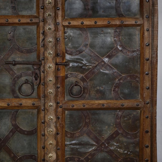 Antique Indian Carved Teakwood and Iron Door, the frame with decorative nailheads, a carved center style with brass...