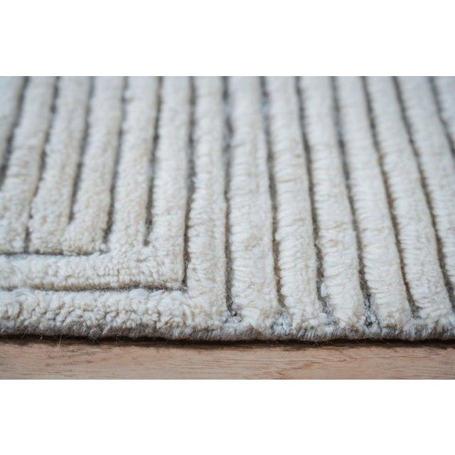 This hand knotted pile rug is crafted from wool and originates from India. The primary color palette includes neutral...
