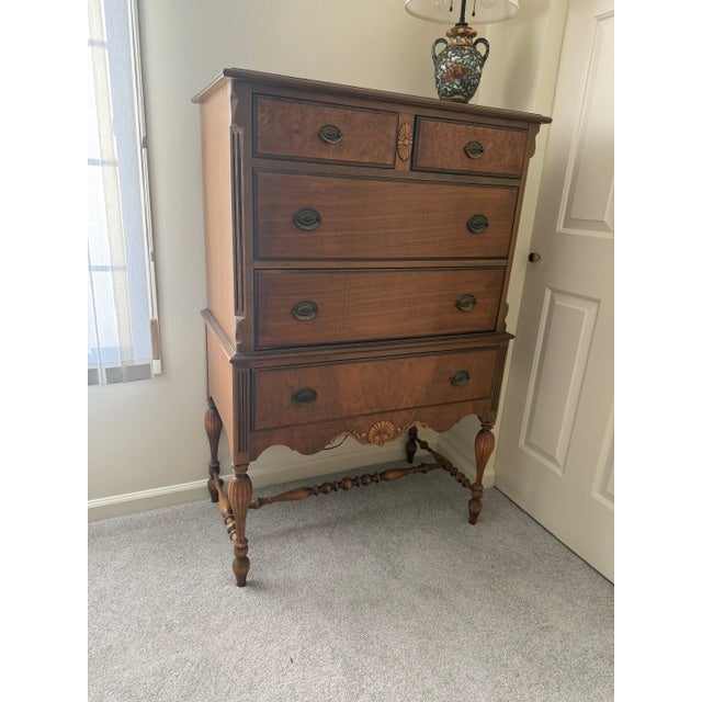 This is a five-drawer highboy/chest on chest dresser featuring burl veneer panels on the top, two small drawers and bottom...