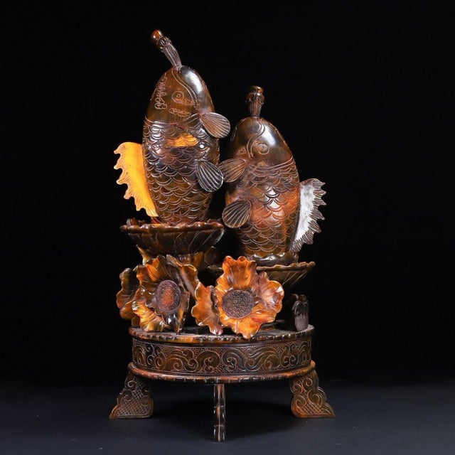A striking and substantial Chinese carved horn sculpture. The piece features two large, detailed carp leaping upwards from...