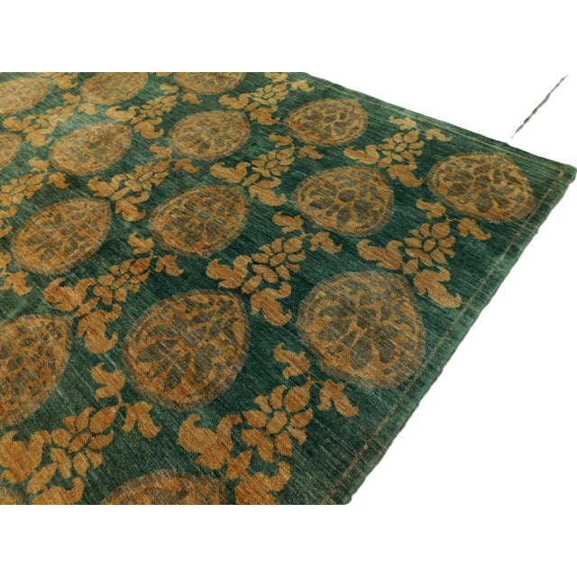 Green field decorated with multiple arrays of stylized flowers. Plush handspun wool pile. Handmade by skilled artisans.