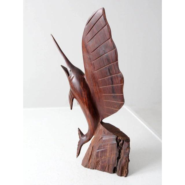 This vintage hand-carved sailfish sculpture is crafted from rich, dark ironwood and poised in a dynamic leaping pose on a...
