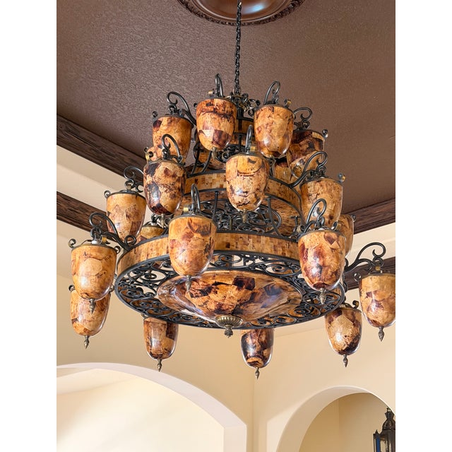 That is a large Maitland-Smith capiz shell / tortoiseshell-style chandelier with wrought iron scrollwork, and it’s the...