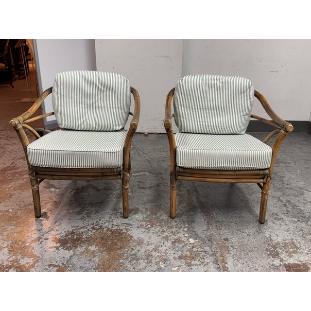 Design Plus Gallery presents a Pair of Circa 1970's Club Chairs from McGuire Furniture. Hand-shaped rattan frames are...