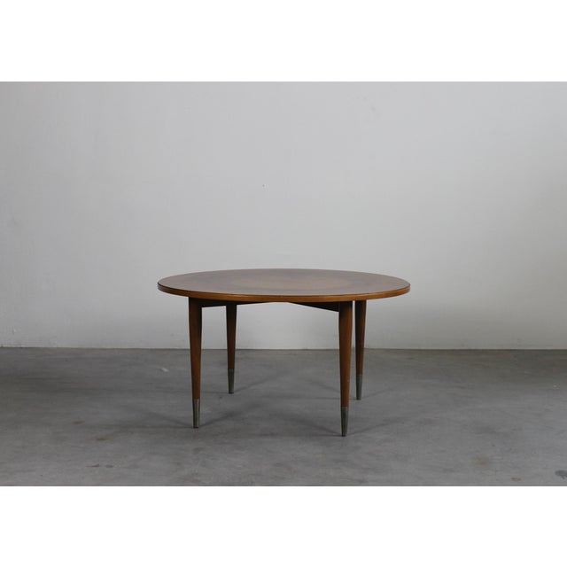 Round coffee table realized in walnut wood with metal details, the tabletop presents an elegant circular decorative motif....