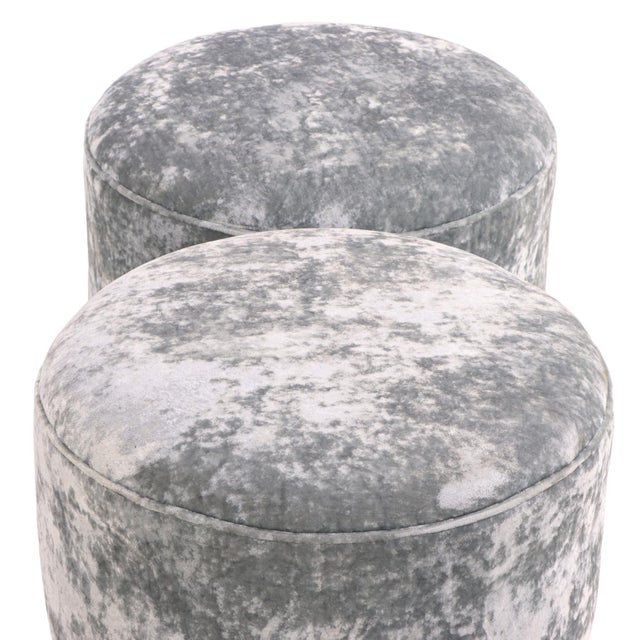 Upholstered in luxurious silver-gray velvet, each stool features a generously padded circular seat raised on four short...