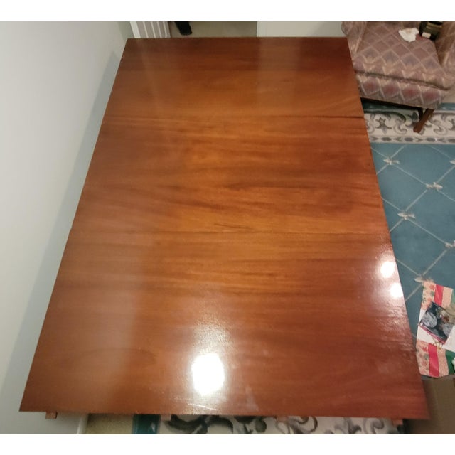 This stately 1920s English gate leg dining table features a mahogany top and legs with a golden satinwood apron. The legs...