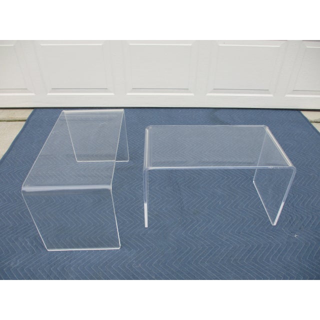 Two acrylic waterfall style low side tables. This pair of mid-century modern tables is ready for use and display. The...