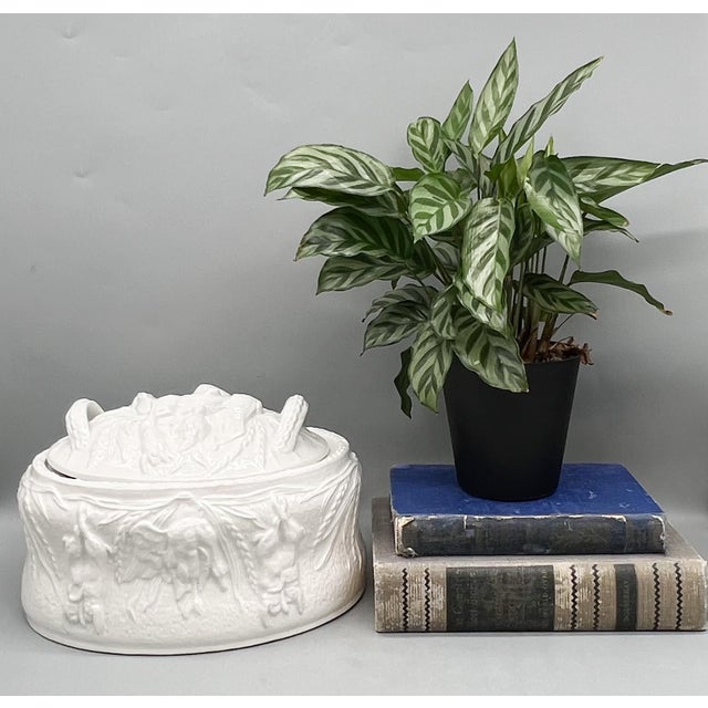 Vintage covered serving bowl crafted in creamy white glazed earthenware, featuring detailed relief scenes of rabbits, a...