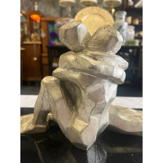 This stunning cubist style sculpture features two lovers embracing. Cast iron with a nickel finish & mounted on a black...