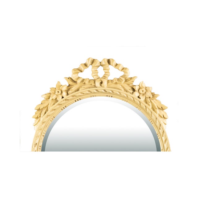 A graceful vintage round wall mirror with a molded plaster frame and an ornate pierced crest detailed with flowers and...