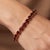 A classic tennis bracelet featuring a continuous row of rich, deep-red oval garnets set in a warm gold-tone sterling...