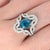 A blue zircon takes center stage in a brilliant electric blue at the heart of this solid 14K white gold ring, framed by...