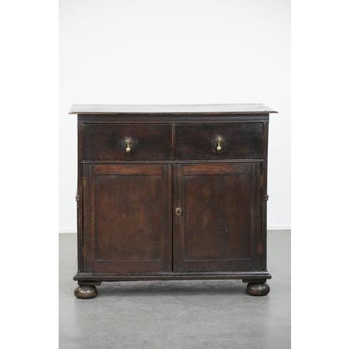 This rare English antique two-door cabinet from the early 18th century with ball feet and a beautiful patina. : This...