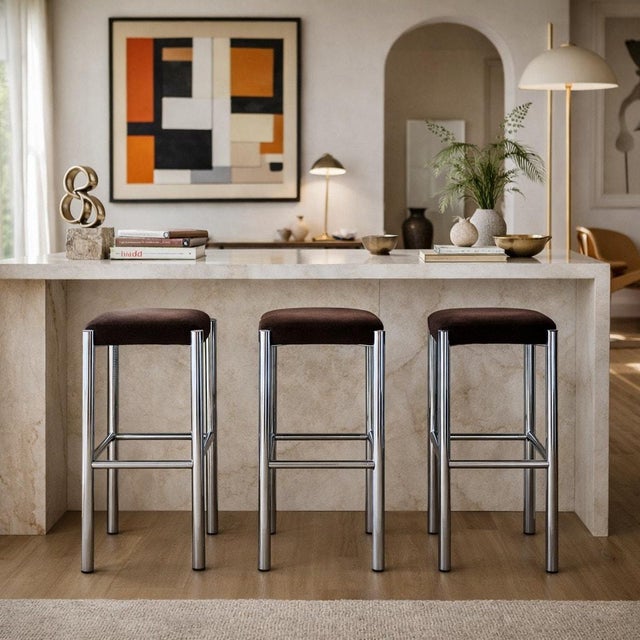 Set of three vintage chrome bar stools with chocolate brown velvet seats. The stools have clean tubular chrome frames with...