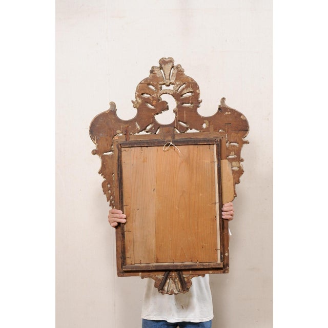 A Continental Baroque style wood carved and gilt mirror from the turn of the 18th and 19th century. This antique wall...