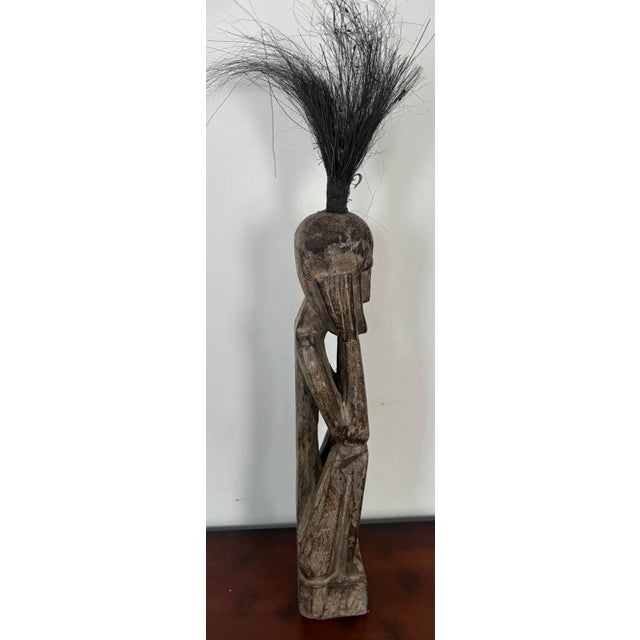 A striking primitive modern sculptural figure with elongated proportions and expressive minimalist features, finished in a...