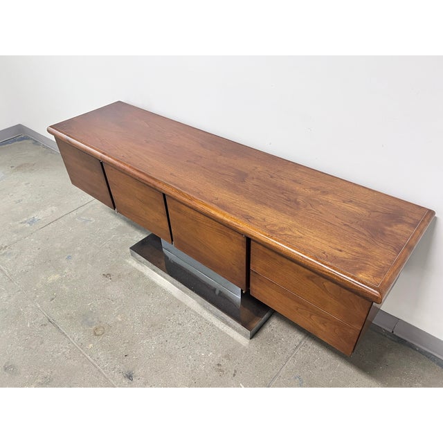 A walnut and polished aluminum credenza in the manner of Warren Platner for Lehigh-Leopold, ca. 1970. It features a...