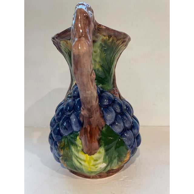 Vintage hand painted ceramic pottery pitcher. Lovely grape pattern with hand that resembles a grape vine. Measures 10"...