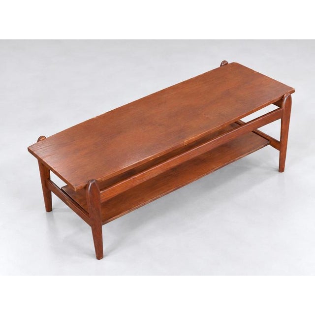 Vintage teak coffee table featuring a stylish and functional design. The table is equipped with a reversible top, allowing...