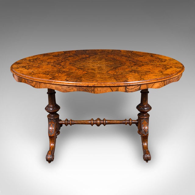 This is an antique display table. An English, burr walnut and mahogany four seat oval centre table, dating to the early...