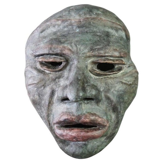 A Mid Century Modern wall sculpture by York offers terra cotta construction and depicts the face of a tribal man, artist...