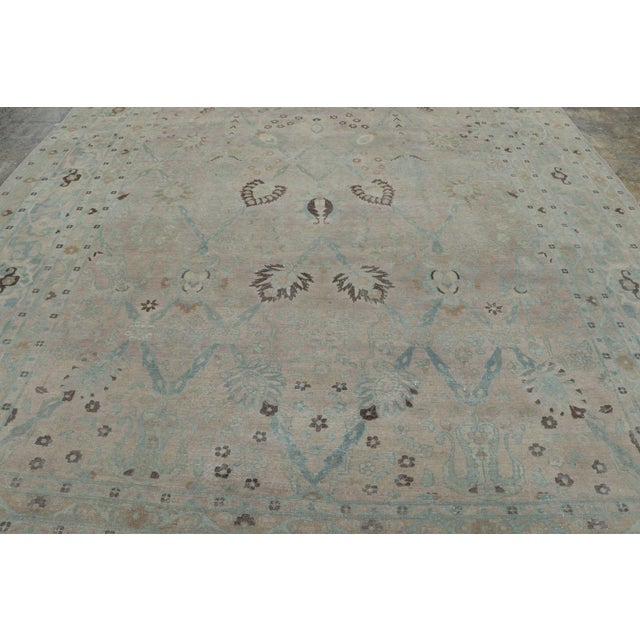 Hand-knotted in wool, this 10x14 antique Mashad rug, circa 1900-1920, is a graceful example of Persian weaving...