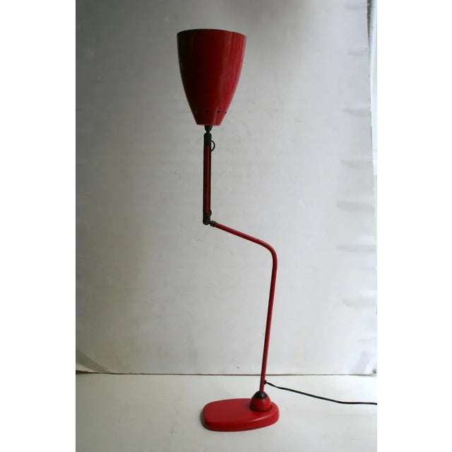 This table lamp from the 1950s features an adjustable arm and red paint. European Plug (up to 250V).The wiring of this...
