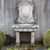 Wall fountain made of antique-patinated natural stone with a profiled back panel and shell-shaped basin. Solid support...