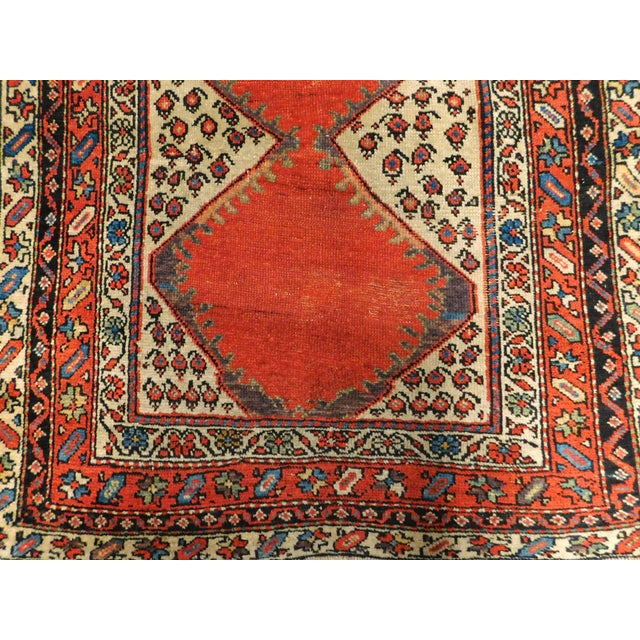 A rare and unusual hand knotted antique Persian rug. Rich in tone red center with paisley like symbol. The lower part of...