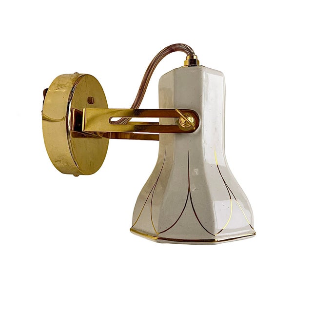Extraordinary wall lamp from the 1980s, Faladesa Spain. It is made of shiny brass and has a ceramic shade with "golden"...