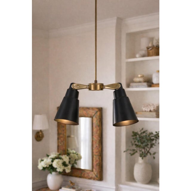 Mid-century modern dual pendant by Lincoln Lighting of Chicago with two black metal cone shades on a brass swivel mount....