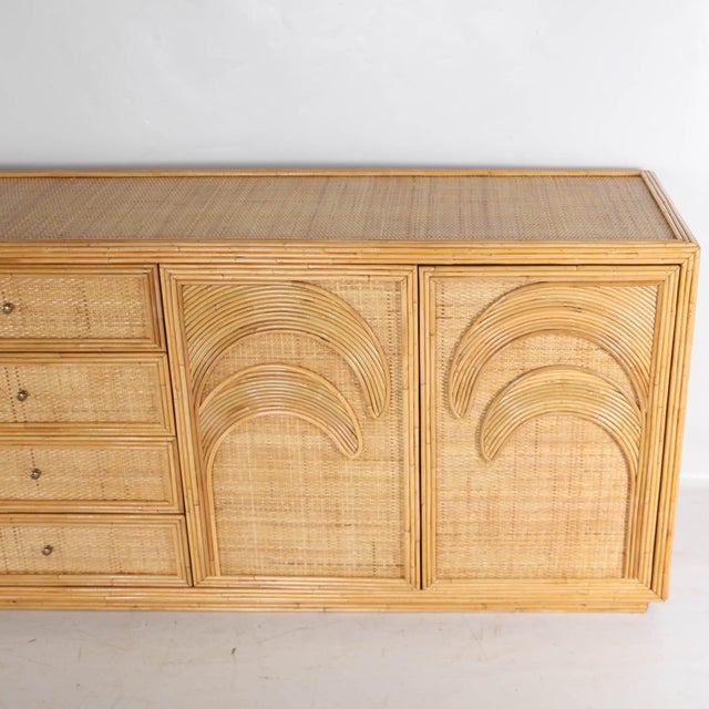 Exceptional rattan and raffia sideboard with palm leaf motifs. Featuring four doors, four drawers, and two interior...
