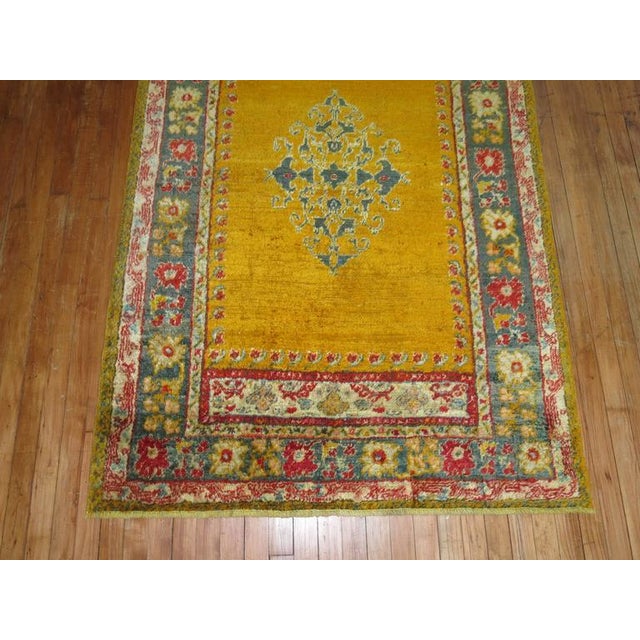 An early 20th century angora wool Oushak rug with a saffron gold colored ground on an open field and center medallion....